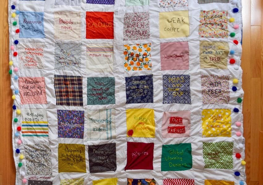 This is a 6 foot by 6 foot handmade quilt that features different colored squares with hand stitched grievances.