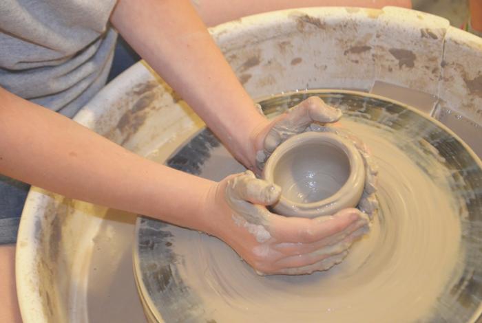 A student's hands working on the pottery wheel.