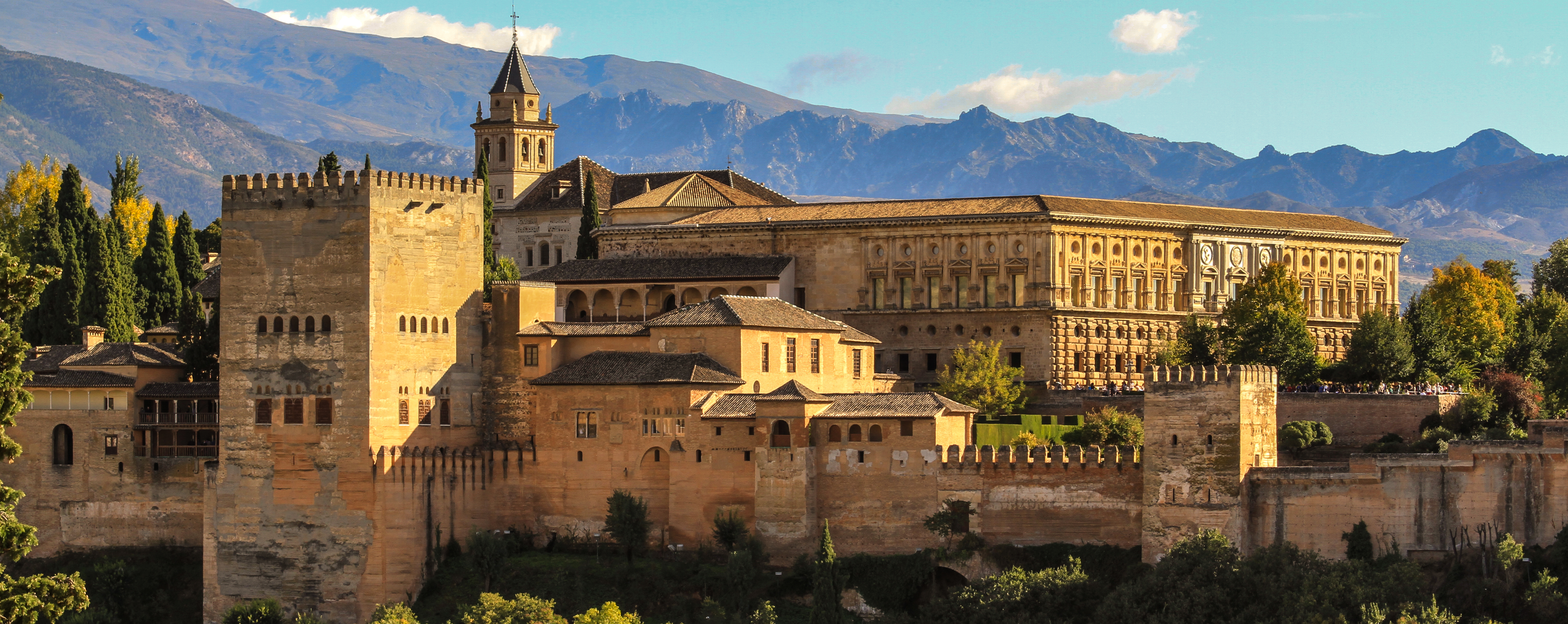 This image is the Alhambra castle, and one-time fortress- in Granada Spain. Behind it are mountains. 