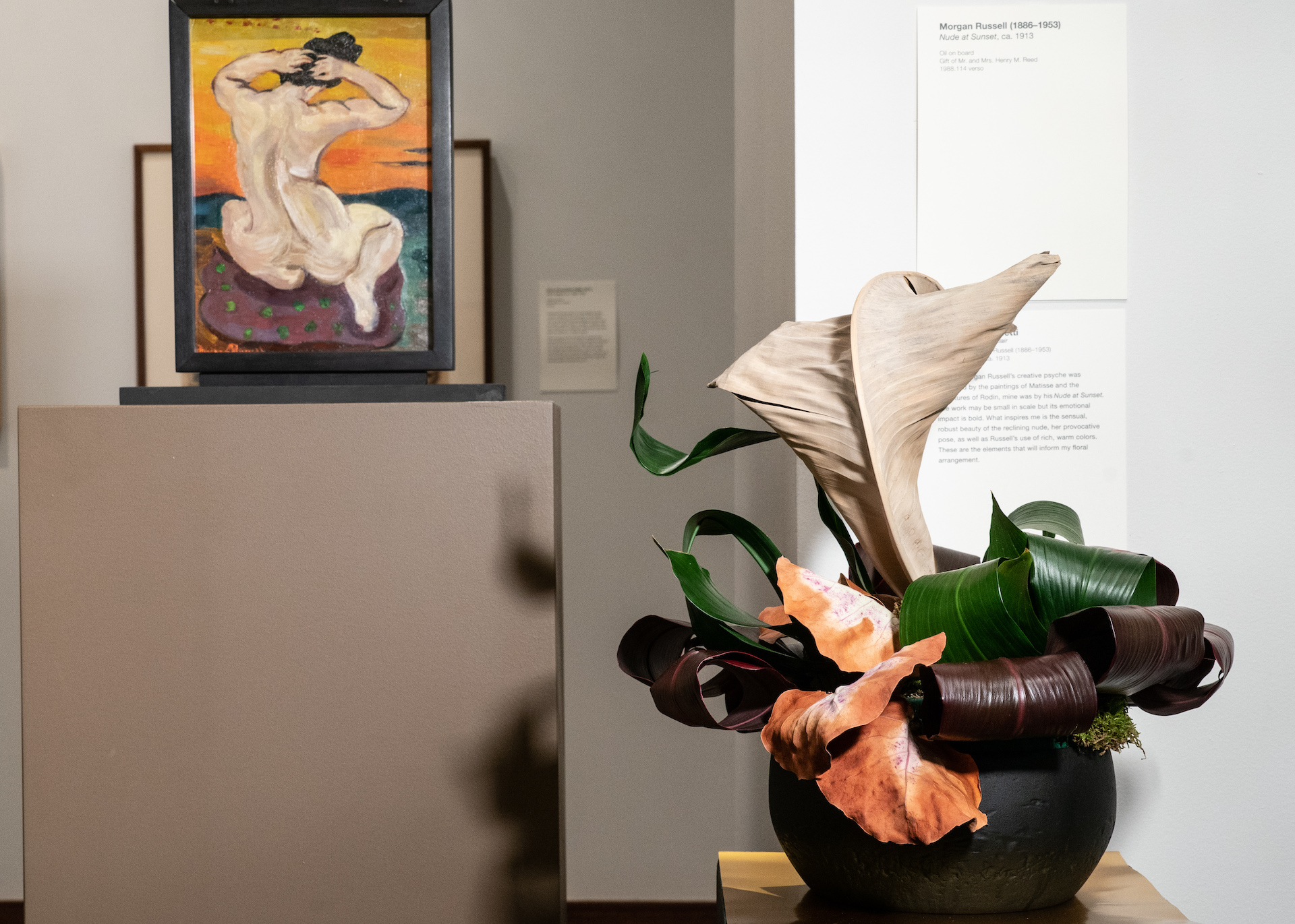 A sculptural floral arrangement in front of the artwork that inspired it in the gallery.