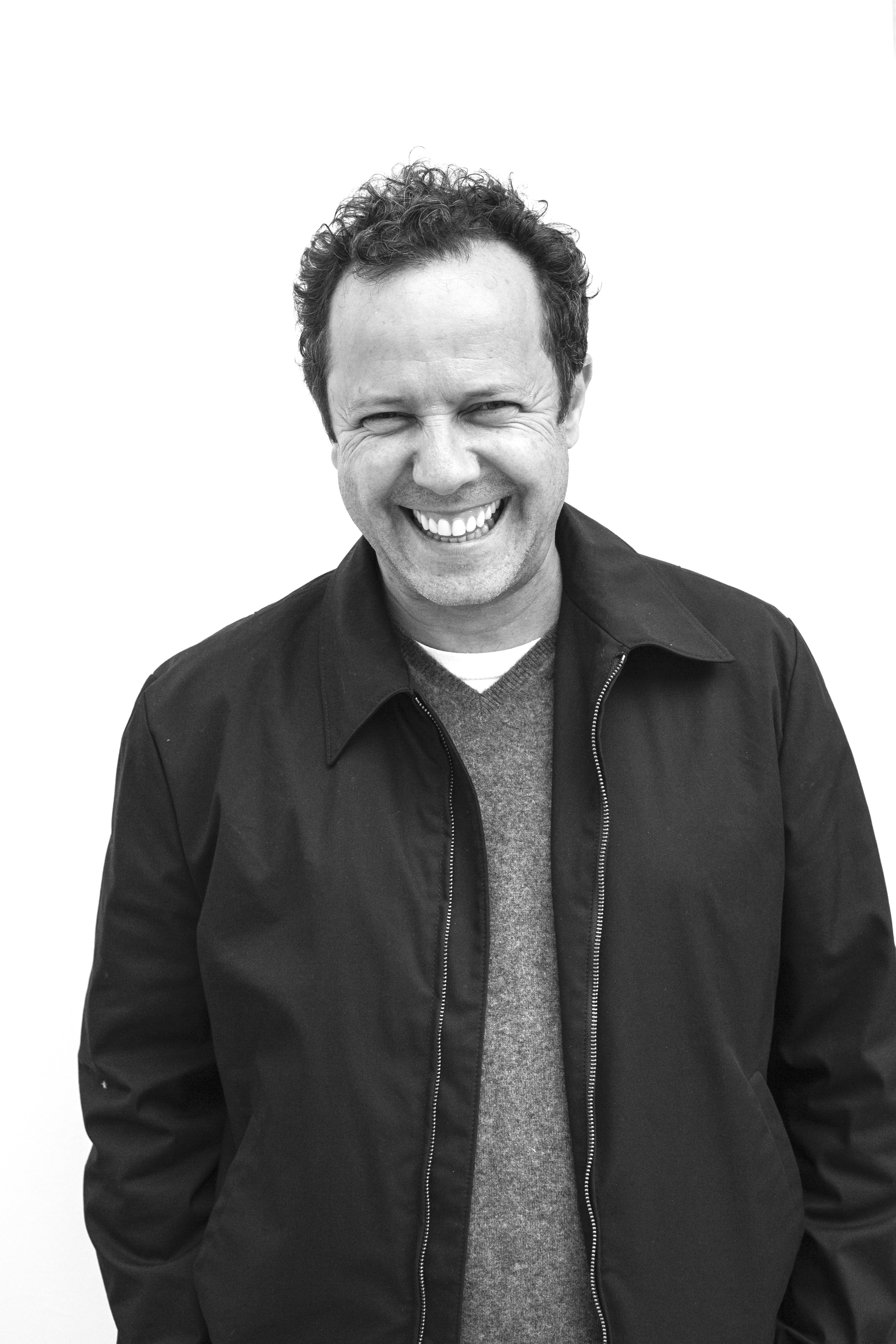 A black and white photo portrait of Vik Muniz laughing