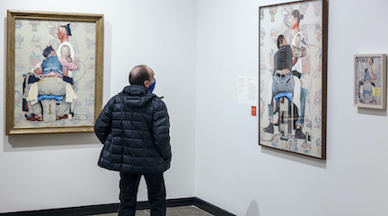 A visitor with their back facing us is looking at norman Rockwell's The Tattoo Artist next to Maggie Meiners' Skin Deep in MAM's gallery.