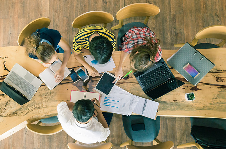 Overhead shot of group working at a table on various projects