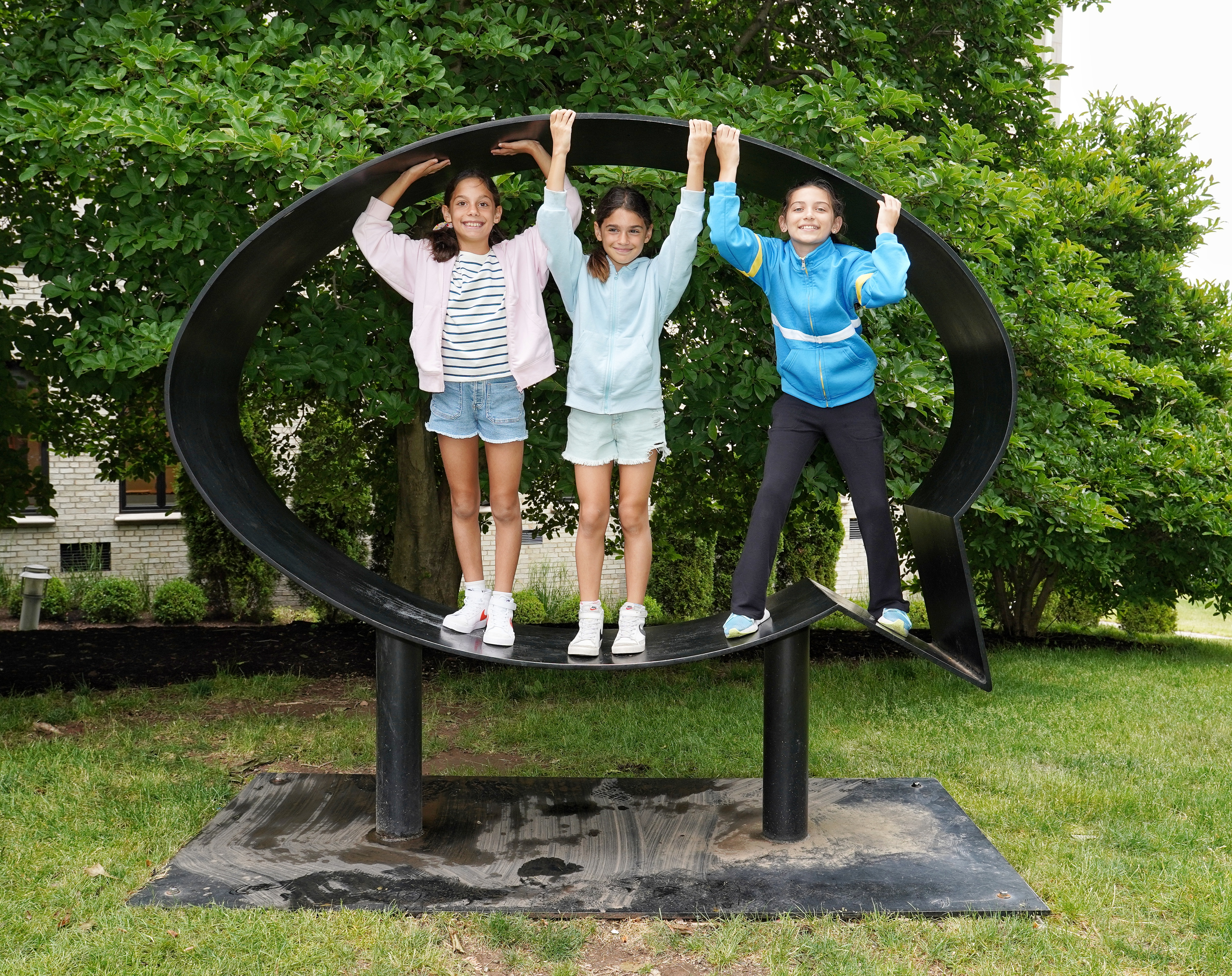 Three girls standing side by side in Hank Willis Thomas' statue, "Ernest and Ruth,"