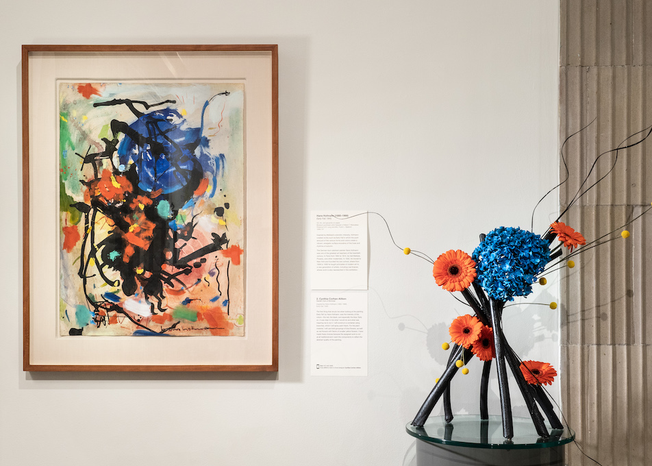 A floral arrangement sits in front and to the right of an artwork in the MAM galleries. This is part of a biennial celebration of floral design.