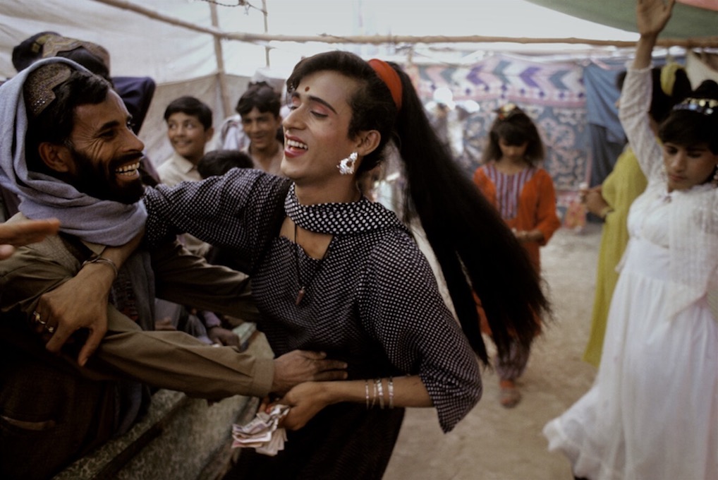 Balochistan, Pakistan. 1997. A trans person and onlooker are playful at the Sibi Mela Camel Festival. Photo by Ed Kashi