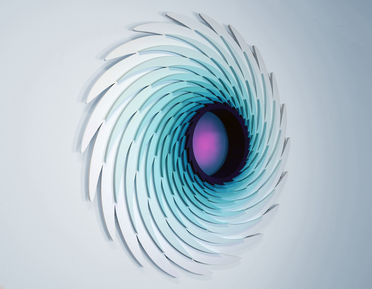 Abstract wall art featuring layered, curved shapes in shades of blue and white, creating a swirling pattern with a dark center.