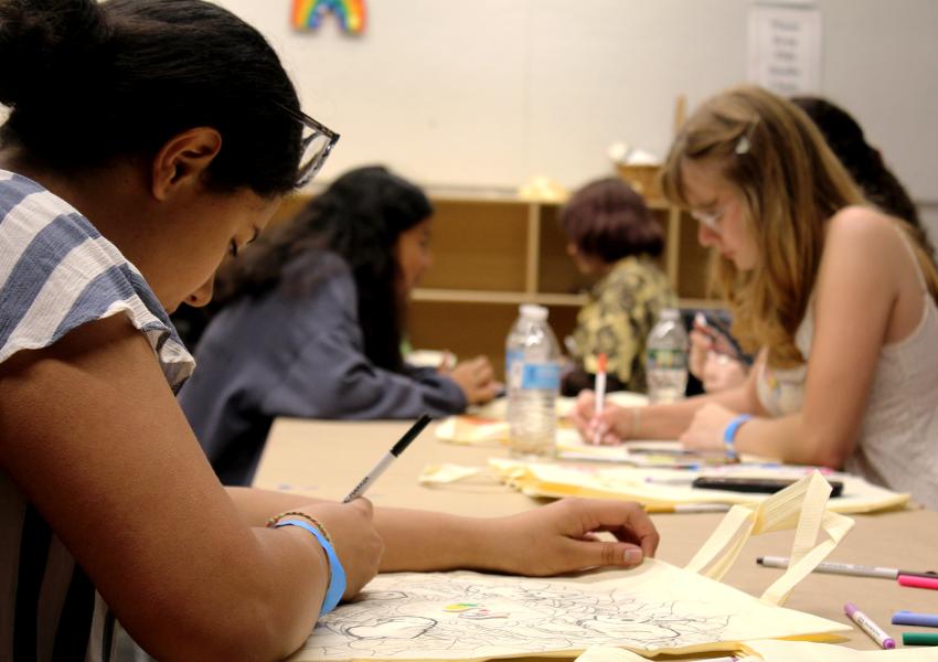 View of a group of teens sitting at a tale in a MAM studio, drawing