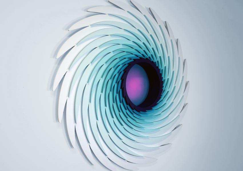 Abstract wall art featuring layered, curved shapes in shades of blue and white, creating a swirling pattern with a dark center.