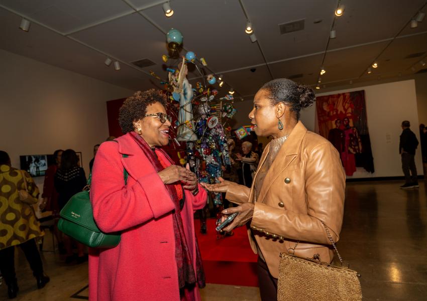 Two women speak to each other in the "Century: 100 Years of Black Art at MAM" exhibition