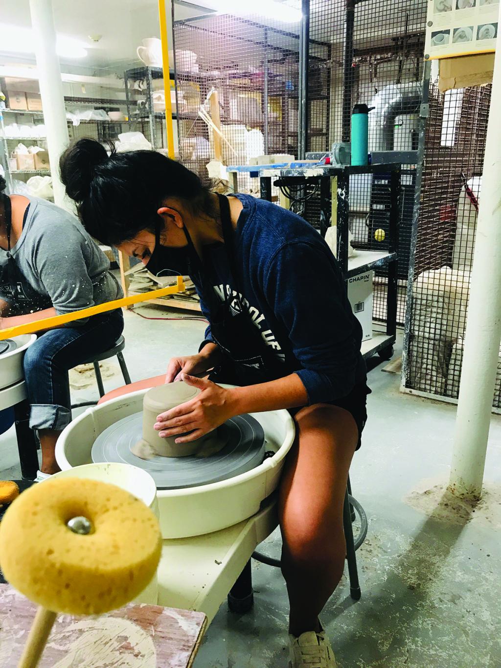 A teen is working on a pottery wheel.