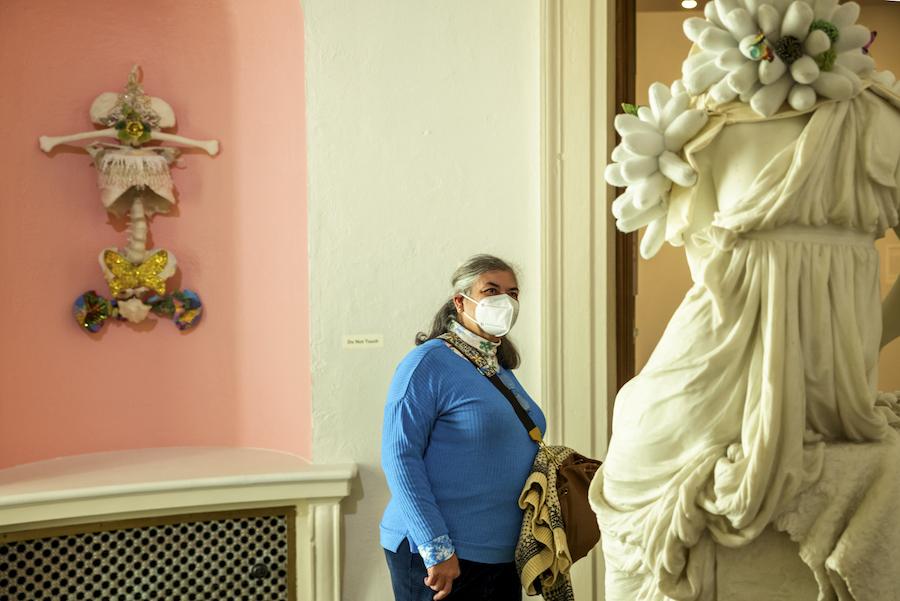 A visitor wearing a mask is looking up at Saya Woolfalk's intervention or addition to the Crown For the Victor statue.