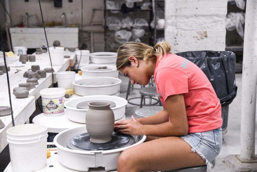 Camper creating a vessel on the wheel as part of SummerART Ceramics Camp