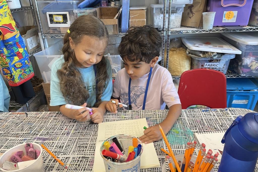 Children at a table with art supplies and a water bottle.