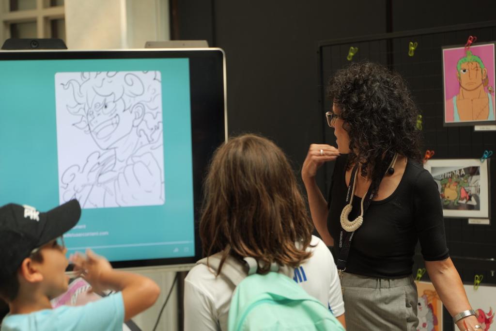 People viewing artwork on a computer screen and wall at an exhibition.