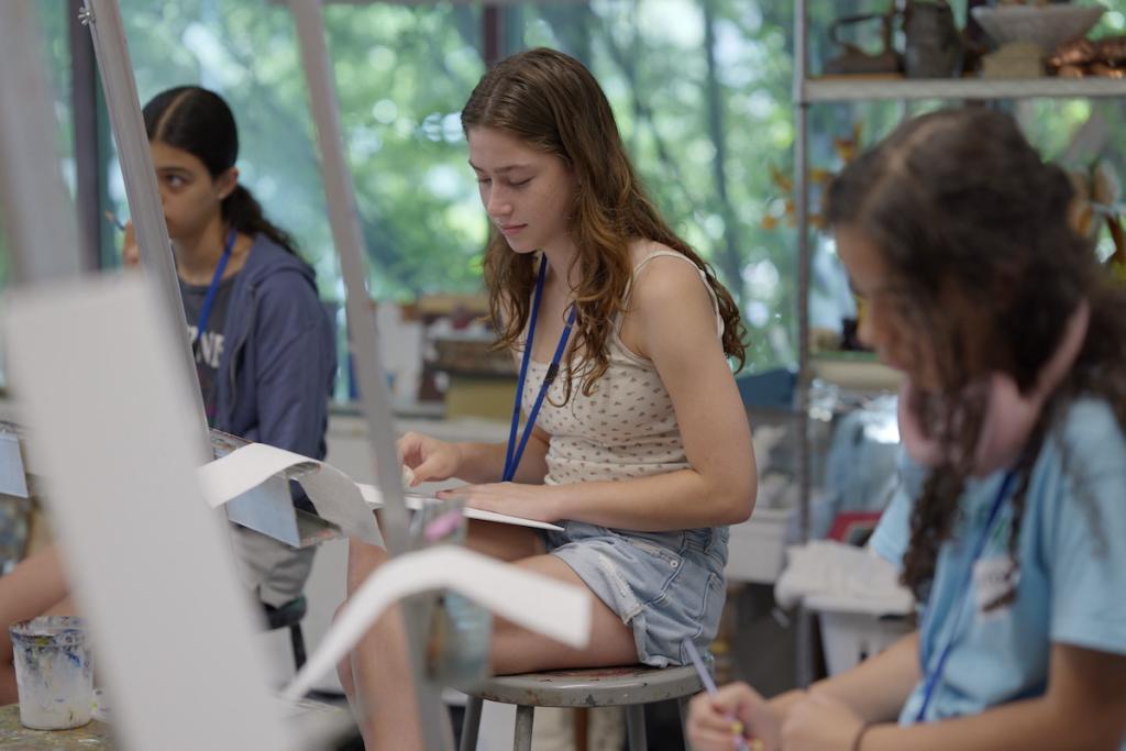 Students in an art class painting on canvases.