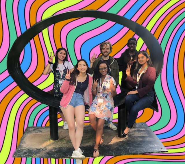 The 2019 teen intern group sitting on a sculpture at MAM with the background photoshopped to be psychedelic rainbow lines.