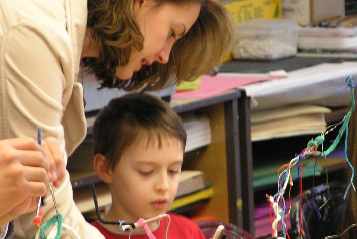 a parent and child are working together on an art project with pipe cleaners.
