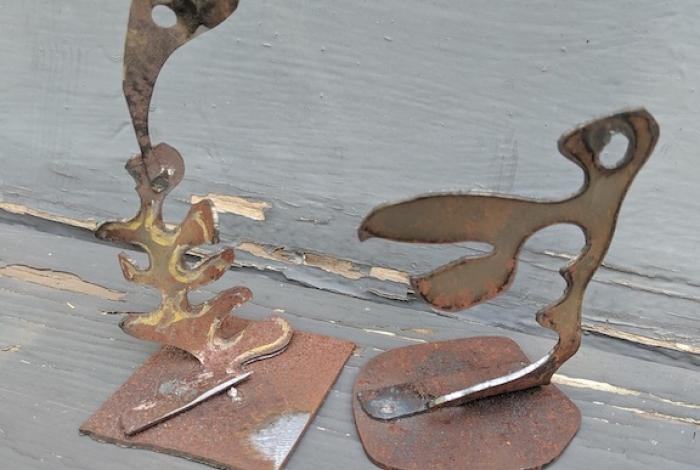 Two small abstract metal sculptures are sitting on a table.