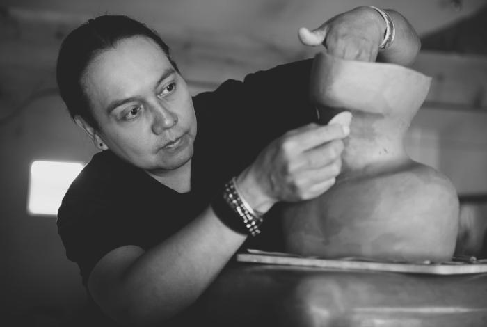 I'm an image! Virgil Ortiz sculpting clay by hand in his studio. Ortiz is focused on his work and not looking at the camera.