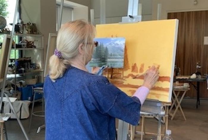 woman painting a landscape in class