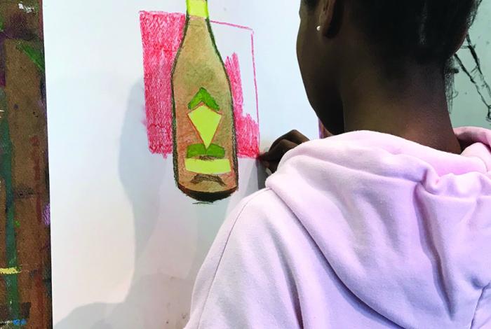 A student is drawing a still life on an easel.