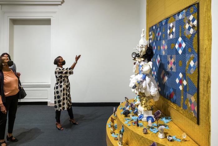 A visitor is gesturing toward a large installation work by Vanessa German in MAM gallery.