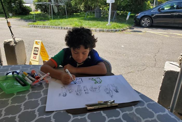A young student is drawing a cartoon characters at camp.