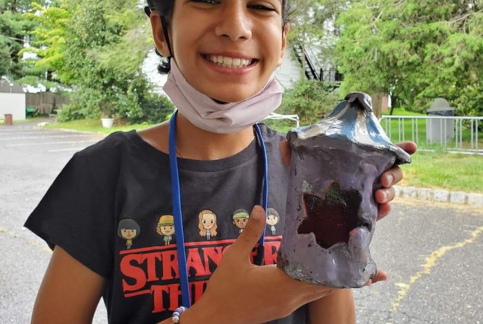 A student holding up their ceramic work.