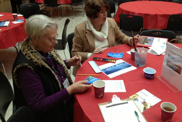 Two women painting at a round table as a part of MAM's Art int he Afternoon program