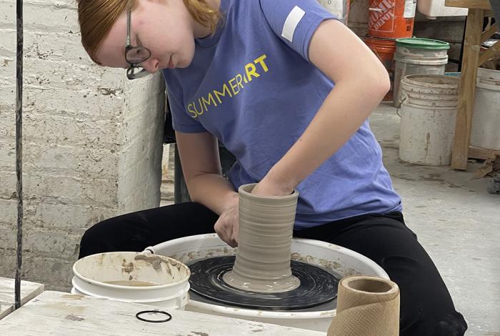 Camper creating a vessel on the wheel as part of SummerART Ceramics Camp