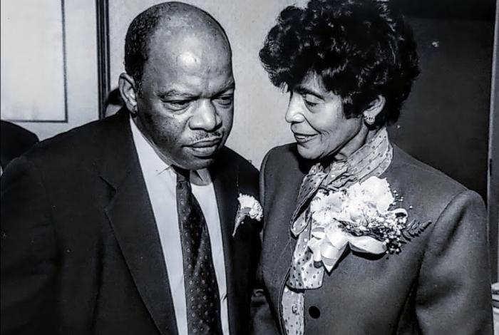 A vintage black and white photo of two people in formal attire with corsages.