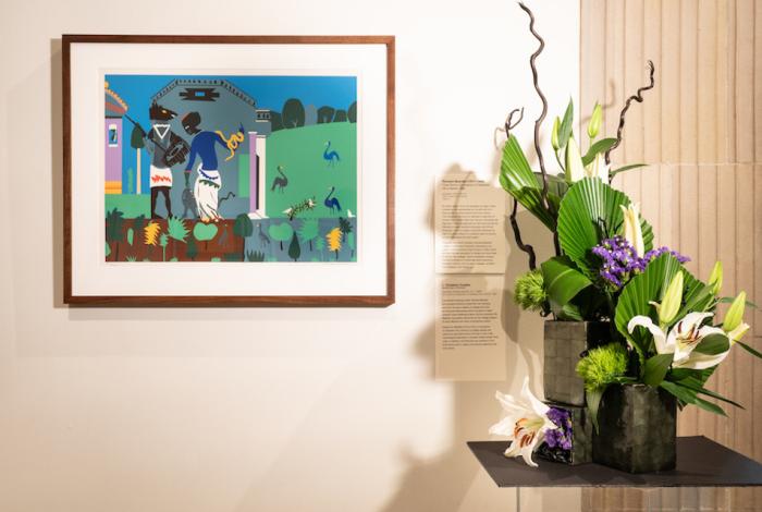 A floral arrangement sitting in front and to the left of an artwork in MAM's galleries. 